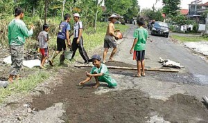 SWADAYA: Warga gotong royong memperbaiki jalan berlubang di Dusun Krajan, Desa/Kecamatan Sempu, kemarin.