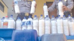 Kanit-Sabhara-Polsek-Srono,-Aiptu-Rahmanto-Yuli-Prasetyo-(kiri),-mengamankan-puluhan-botol-tuak-kemarin.