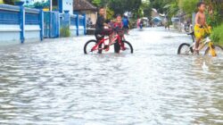 Sejumlah-anak-anak-bersepeda-di-jalan-raya-yang-tergenang-air-di-Dusun-Krajan,-Desa-Tembokrejo,-Kecamatan-Muncar,-Banyuwangi,-kemarin.
