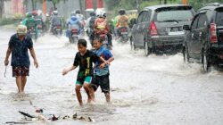 Beberapa-anak-bermain-di-tengah-genangan-air-hujan-di-Jalan-Yos-Sudarso,-Kecamatan-Kalipuro,-Banyuwangi,-siang-kemarin