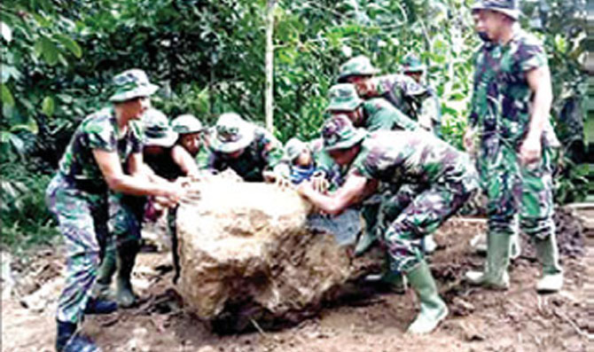 Anggota-TNI-AD-mendorong-batu-besar-yang-menghalangi-pembangunan-jalan-di-Desa-Pesucen,-Kalipuro.