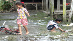 Dua-anak-bermain-di-bekas-lokasi-luapan-air-di-Dusun-Silirsari,-Desa-Kesilir,-Kecamatan-Siliragung,-Banyuwangi,-siang