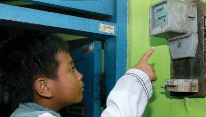 Salah-seorang-pelanggan-PLN-sedang-mengamati-meteran-listrik-untuk-memantau-penggunaan-listik-di-rumahnya.