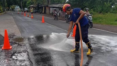 jalan-raya-benelan-kidul-licin-gegara-solar-tumpah!-pengendara-sampai-jatuh,-damkarmat-banyuwangi-turun-tangan