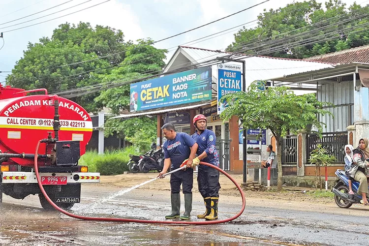 jalan-berlumpur-di-jembatan-mayit-dikeluhkan-warga,-damkarmat-genteng-kerahkan-ribuan-liter-air